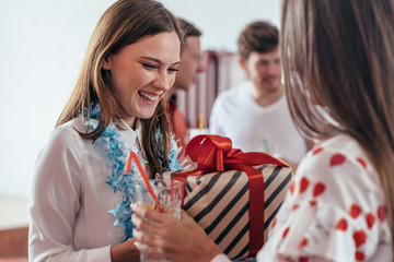 Girl gives a gift to her friend during the new year party.