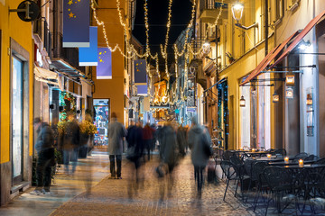 People walk along a street illuminated by christmas lights.