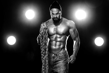 Fototapeta na wymiar Men fashion. Close-up portrait of a brutal bearded man topless in a leather jacket with chains. Athlete bodybuilder on black background.