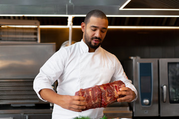 unrecognizable young African chef standing in professional kitchen in restaurant preparing a meal...