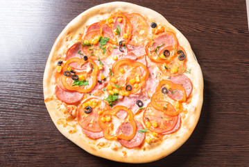 Cheap pizza, with tomatoes, peppers, ham, and olives.