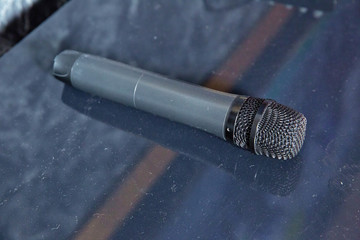 Close up Microphone on the table, concept of speaker or teacher preparation to speak in seminar class room . A black microphone is on the table .