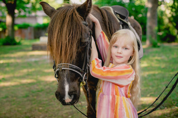 Obraz premium Female rider and horse in the open air. portrait of a beautiful young girl with her stallion, outdoors. girl hugging and caressing the animal