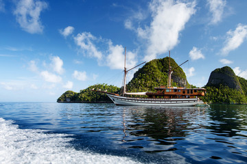 Fototapeta premium Sail boat between islands of remote archipelago Pulau Wayag, Raja Ampat, Indonesia