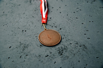 Bronze Medal lie on a stone background. Bronze medal on a dark background. The concept of...