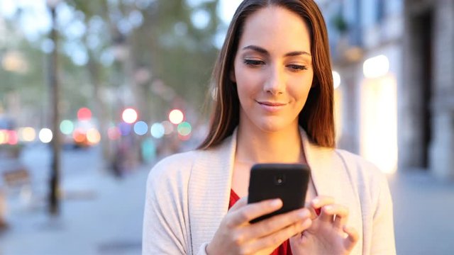 Front view of a serious woman walking browsing smart phone content at evening 