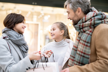 Fototapeta premium Happy family of three in casualwear discussing what they bought after shopping