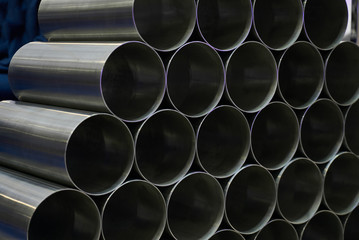 Steel pipes against industrial blurred background, close-up