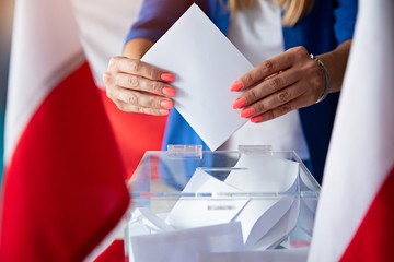 Woman putting her vote to ballot box. Poland political elections