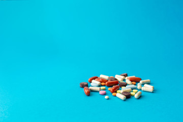 A scattered handful of colored pills on a blue background. Medical concept