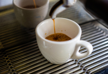 background. coffee machine makes coffee in a white cup