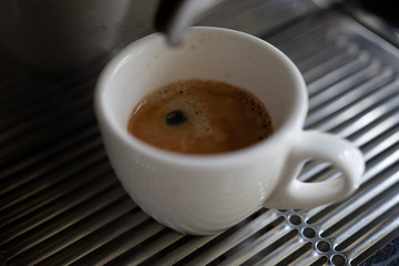 background. coffee machine makes coffee in a white cup