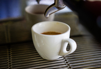 background. coffee machine makes coffee in a white cup