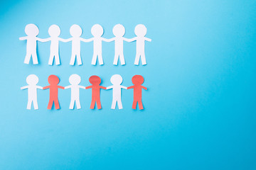 White and red paper people holding hands. Blue background. Froma bove