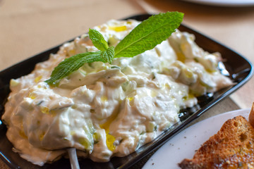 Tzatziki, dip or sauce from Southeast Europe and Middle East made of salted strained yogurt mixed with cucumbers, garlic, salt, olive oil, vinegar or lemon juice, and dill, mint, parsley and thyme.