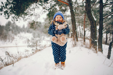 Kid in a winter forest. Girl in a blue hat. Child playing with toy
