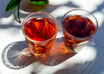 Young rose wine served outside in garden on white table with fresh orange in sun lights