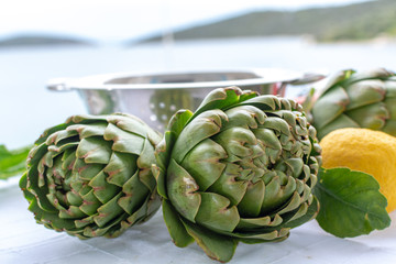 Fototapeta premium Heads flowers of fresh raw artichokes plants from artichoke plantation in Argolida, Greece ready to cook with lemon