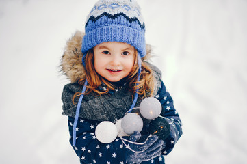 Kid in a winter forest. Girl in a blue hat. Child with a garlands
