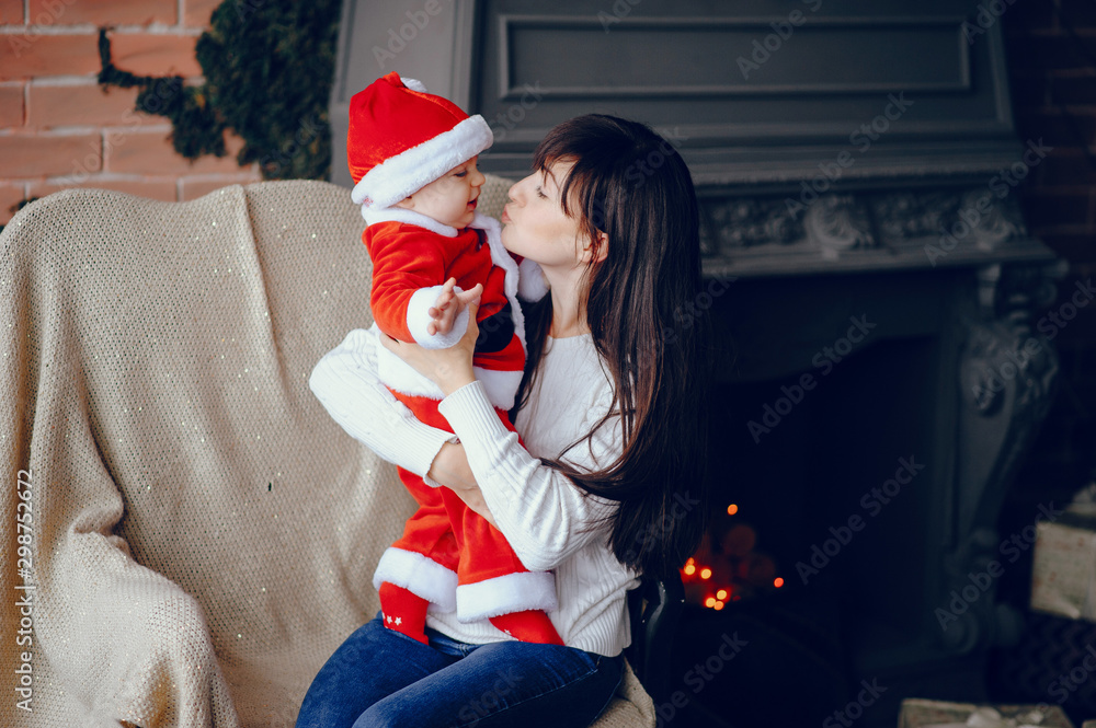 Sticker Beautiful mother in a white sweater. Family in a christmas decorations. Little boy in a santa costume