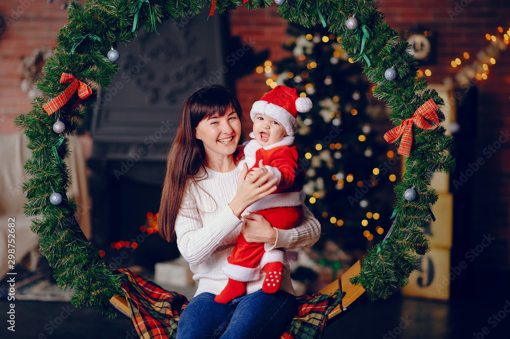 Poster Beautiful mother in a white sweater. Family in a christmas decorations. Little boy in a santa costume