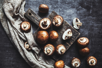 Royal mushrooms on a black background with a vintage board and a kitchen towel
