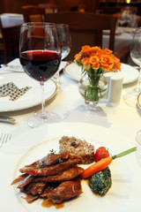 Meat meal with vegetables, rice and red wine on the restaurant table