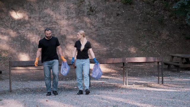 two volunteers who are a couple collecting trash in the community park as a weekend activity