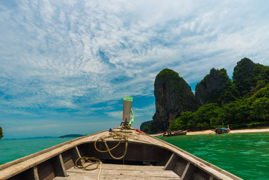 Wooden boat travel into the green rocky island sea