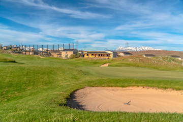 Scenic view of golf course and homes against blue sky and clouds on a sunny day