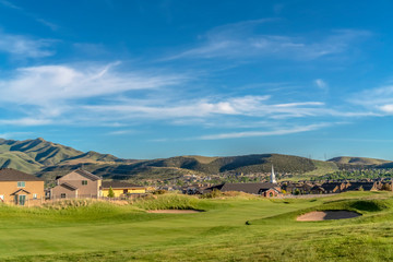 Sand trap and fairway at a golf course with mountain and homes in the background