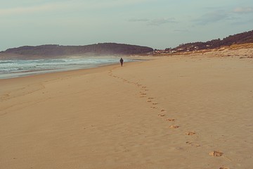 Fototapeta na wymiar Playa solitaria e idílica una tarde de otoño una persona lejana deja sus huellas en la arena