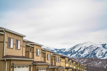 Townhouses with wall sidings and white garage doors against snowy mountain