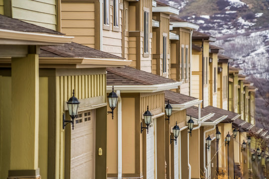 Close Up Of Townhouses Exterior With Wide Garage Doors And White Wall Sidings