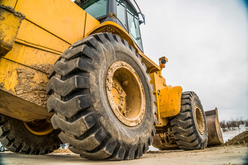 Focus on the black rubber wheels of a yellow bulldozer at a construction site