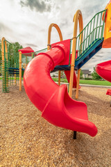 Focus on the colorful playground equipment at a park with red closed tube slide