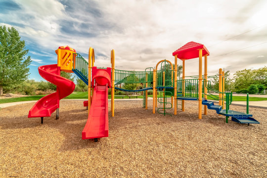 Focus on empty childrens playground at a park with red slides and climbing bars