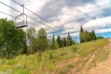 Chairlifts in Park City with a scenic aerial view of greenery during off season