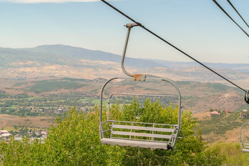 Close up of chairlift with aerial view of Park City ski resort during off season