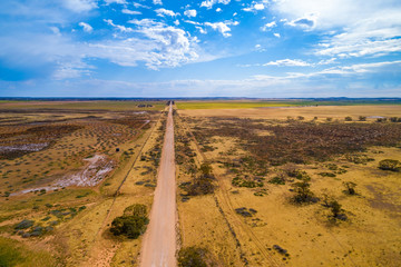 Straight unsealed road passing through Australian outback - aerial view