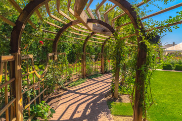 Wooden arbor at a wedding venue with lush green plants and stone brick pathway