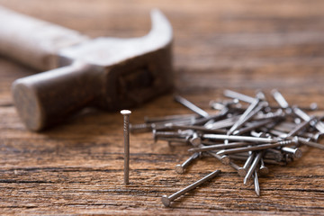 Selective focus of Steel nails and hammer on wooden background  with sunlight