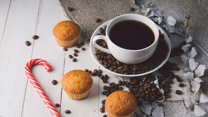 Close up still life, cup of coffee with muffins. Freshly baked delicious muffins and cup of coffee on wooden table. Cup of fresh aromatic coffee and cupcake at table in cafe.