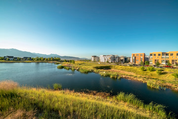 Beautiful lake amid grassy terrain with homes and buildings in the distance