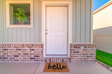 Front door and porch of home with hello mat