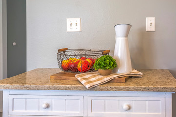Pitcher potted plant plaid cloth and fruit basket with apples on a wooden board