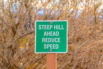 Steep hill ahead reduce speed road sign