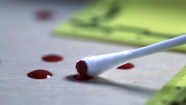 Macro shot of forensic csi police officer collecting blood sample with buccal swap as evidence on crime scene