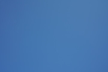 Sky in the daytime, on a clear day, and a thin white cloud drifting along the wind.