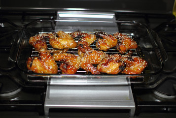 Baked teriayki chicken wings from the oven resting on the stove top in a home kitchen.